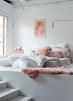 a bedroom with white walls and stairs leading up to the second floor, along with pink furniture