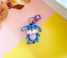 a crocheted stuffed animal keychain hanging on a pink and yellow background