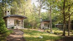 two small cabins in the woods surrounded by trees and grass, one has a door to another room