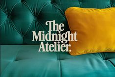 a green couch with a yellow pillow and the words the midnight atelier on it