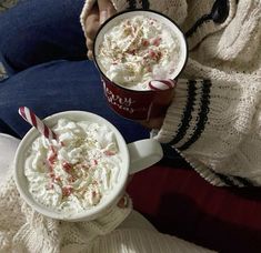 two cups of hot chocolate with whipped cream and candy canes