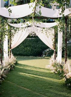 an outdoor wedding ceremony with white drapes and flowers