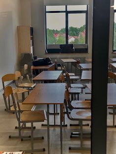 an empty classroom with desks and chairs in front of a window overlooking the countryside