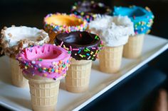 several ice cream cones with sprinkles and chocolate frosting on them are sitting on a white plate