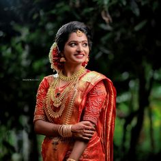 a woman in an orange and gold sari is posing for the camera with her hands on her hips