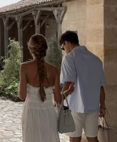 a man and woman are walking down the street with handbags in their hands as they talk to each other