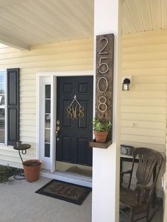 the front door of a white house with black shutters and a wooden rocking chair