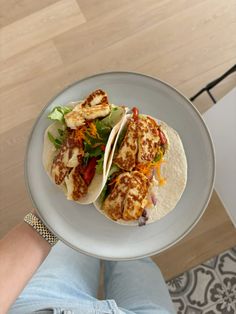 a person holding two tacos on top of a plate