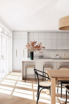 an open kitchen and dining room with white walls, wood floors and floor to ceiling windows