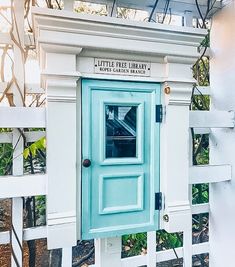 a small blue door on the side of a white fence