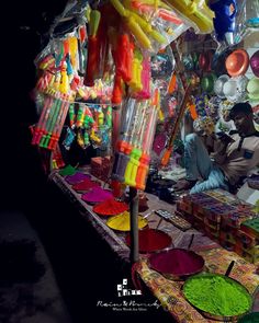 a man sitting in front of a table filled with different colored items