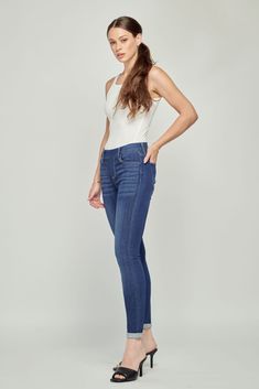 a woman in high rise jeans and heels posing for the camera with her hands on her hips