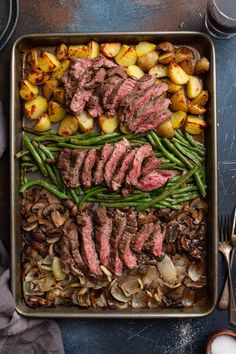 steak, potatoes and green beans in a roasting pan with utensils on the side