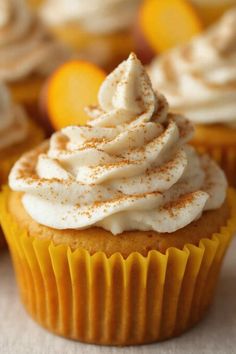 cupcakes with white frosting and orange zest on top sitting on a table