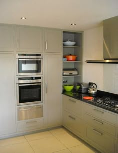 a kitchen with white cabinets and black counter tops is pictured in this image, there are two ovens on the wall