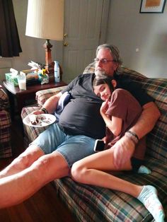 a man and woman sitting on top of a couch next to each other in a living room