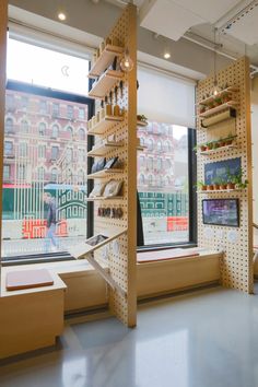 the inside of a store with shelves and plants on display in front of large windows