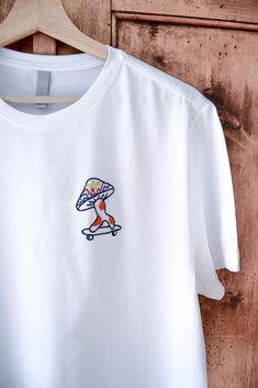 T-shirt blanc « FREE MUSHIE » EDITION LIMITÉE T-shirt (F/M) unisexe , brodé à la main, taille X-S-M-L-XL - 100% coton- tissus doux et de qualité.  Chaque pièce est réalisée avec un design artistique unique.  Démarquez-vous avec une tendance originale et trouvable nulle par ailleurs.  Hi, je suis Melissa, artiste dans le textile et illustratrice. Mon métier est  d'associer l'Art et la mode pour créer des pièces hors du commun et de  qualité. Les vêtements que je choisis sont recyclés ou neufs de haute qualité.  La liberté, la sagesse, l'humour et l'amour sont les valeurs que je souhaite partager.  Devenez aussi unique que mes créations.  Temps de création : 4 heures Instagram : @brodern.art Merci d'avoir visité mon profil <3. Casual White T-shirt With Embroidered Logo, White Embroidered Logo T-shirt For Summer, White Embroidered Logo T-shirt For Streetwear, White T-shirt With Embroidered Logo For Streetwear, Custom Embroidered Cotton T-shirt For Streetwear, White Embroidered T-shirt For Summer, Casual T-shirt With Multicolor Embroidery And Logo, Relaxed Fit T-shirt With Embroidered Logo For Summer, White Embroidered Casual Shirt