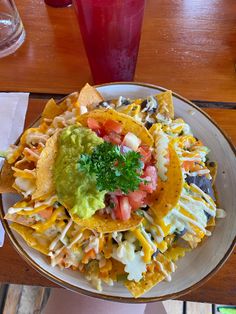 a white plate topped with nachos and guacamole on top of a wooden table