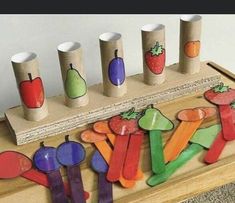 a wooden table topped with lots of cut out fruit and vegetables next to cups on top of each other