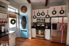 a kitchen decorated for christmas with wreaths on the door and other decorations around the stove