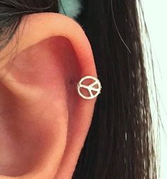 an ear piercing with a peace sign on it