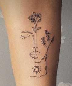 a woman's leg with a flower and face tattoo on the left side of her thigh