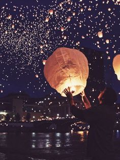 people releasing lanterns into the sky at night with lights on them and in the air