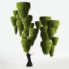 a woman standing in front of a bunch of green plants hanging from the ceiling above her head