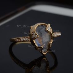 a gold ring with an oval shaped labradorite surrounded by diamonds