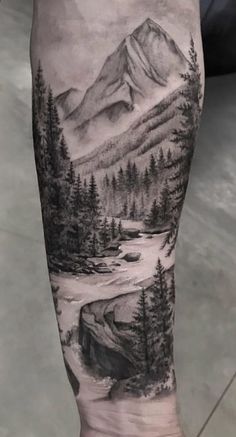 a man's leg with a mountain scene on it and trees in the foreground