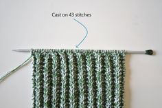 the knitting needle has been hooked up to an object that is knitted in green and white yarn