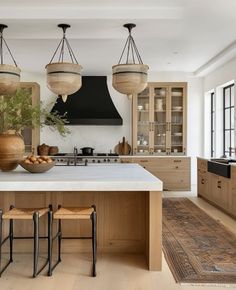 a large kitchen with wooden cabinets and white counter tops, two hanging lights above the island