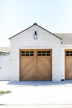 two wooden garage doors in front of a white brick building