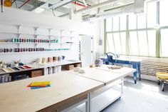 a room with lots of crafting supplies on the tables and shelves in front of large windows