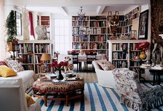 a living room filled with lots of furniture and bookshelves full of books on top of them