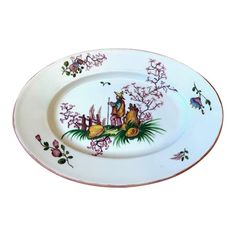 a white plate with pink flowers and birds on the rim, sitting in front of a white background