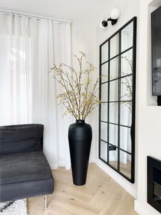 a black vase sitting on top of a hard wood floor next to a gray couch