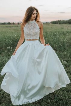 a woman in a white dress is walking through the grass