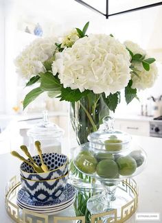 a vase filled with white flowers sitting on top of a table next to plates and utensils