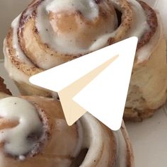 some cinnamon rolls with icing on top of each other and an arrow pointing to the left