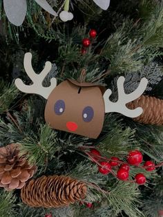 an ornament hanging from the top of a christmas tree with pine cones and red berries