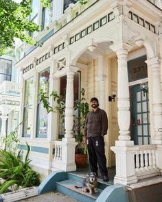 a man standing in front of a house with his dog