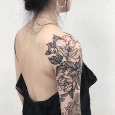 a woman's shoulder with flowers and leaves tattooed on her left upper half sleeve