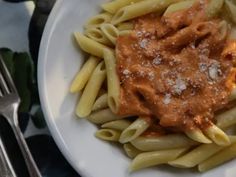 pasta with sauce and parmesan cheese on a white plate next to silverware