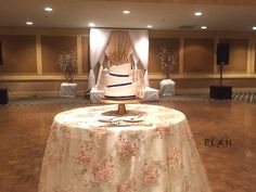 a wedding cake on top of a table in a room with white linens and drapes