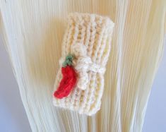 a crocheted cell phone case with a red pepper on it's side