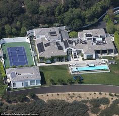 an aerial view of a house with a tennis court in the yard and pool area