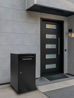 a black mailbox sitting in front of a gray door on the side of a building