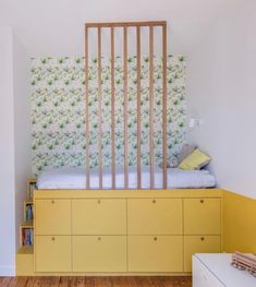 a bedroom with yellow furniture and floral wallpaper on the walls, along with wooden flooring